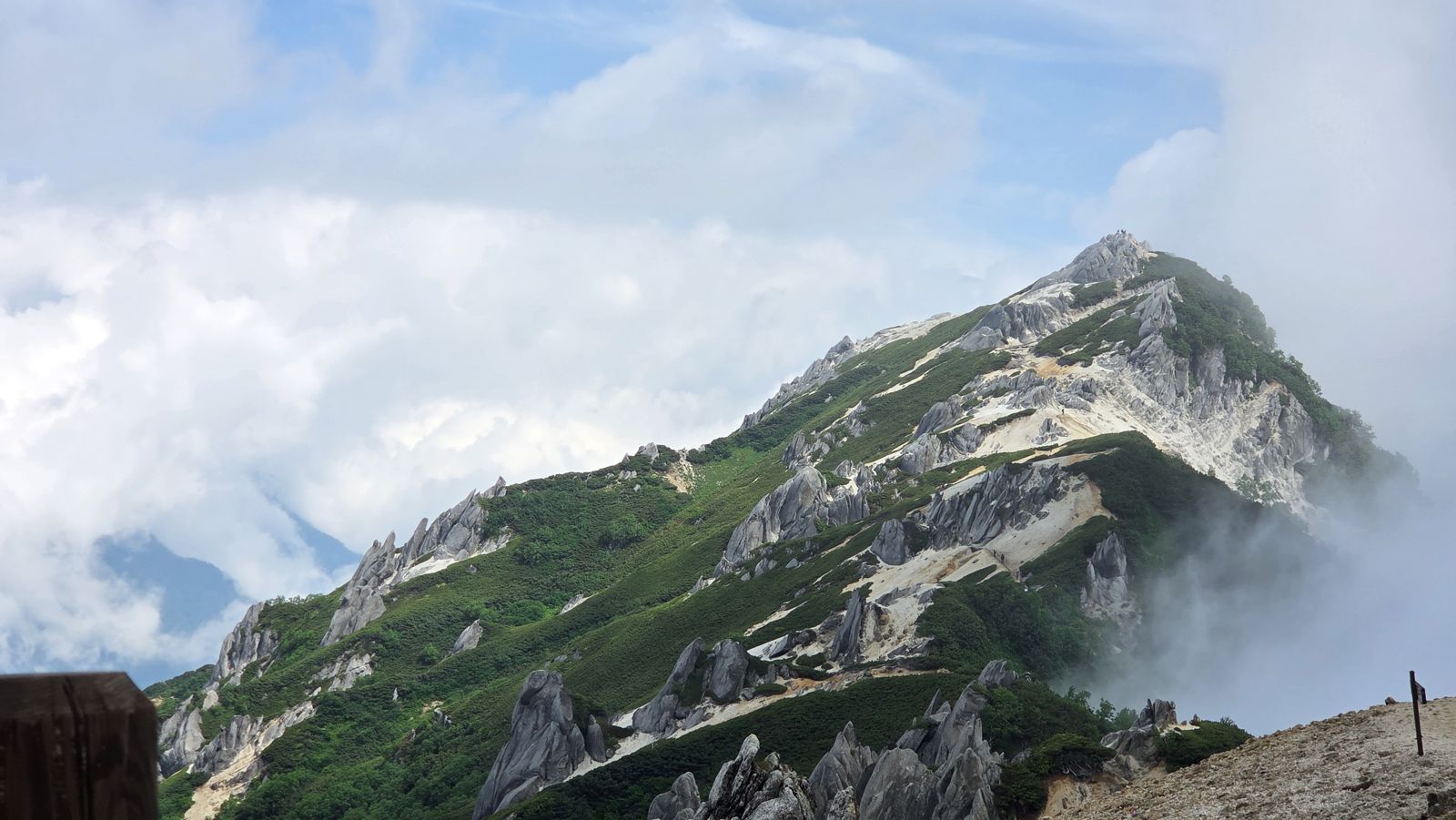 白い花崗岩の燕岳の稜線と、緑の斜面にかかる雲